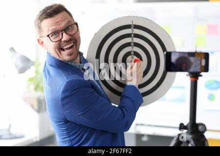 Homme d'affaires jouant aux fléchettes devant l'appareil photo du téléphone portable Banque D'Images
