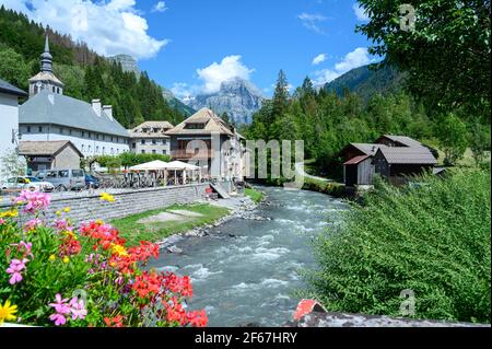 Ruisseau sauvage qui coule à travers la ville avec église. Journée ensoleillée dans la vallée de la montagne. Beauté de la région des montagnes de Giffre, France. Banque D'Images