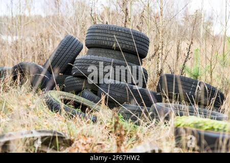 Pile de vieux pneus mis au rebut sur l'herbe Banque D'Images