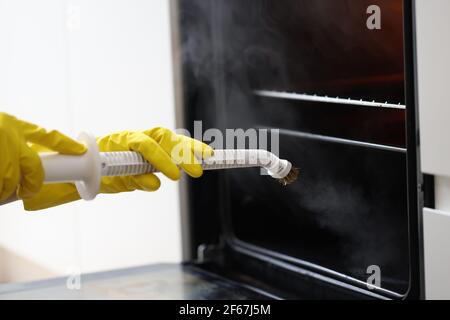 Homme en gants jaunes, lave-linge four avec vadrouille à vapeur, gros plan Banque D'Images