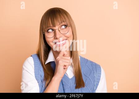 Photo portrait d'une femme curieuse qui a l'air d'un espace vide rêvant de sourire isolé sur fond beige pastel Banque D'Images