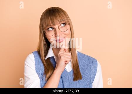 Photo portrait de la femme curieux regardant l'espace de rédaction touchant le menton rêvant isolé sur fond beige pastel Banque D'Images