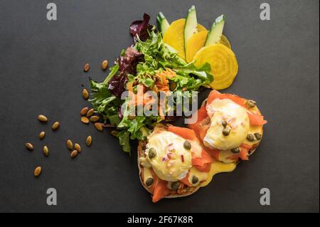 A West Coast oeufs Benedict, oeufs pochés, sauce hollandaise, saumon fumé, oignons, et câpres. Banque D'Images