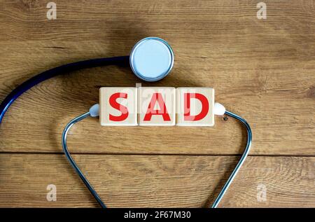 TRISTE, symbole de trouble d'anxiété sociale. Mots-clés « SAD, trouble d'anxiété sociale » sur des cubes sur un beau fond de bois. Médical, psychologique et Banque D'Images