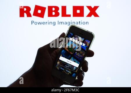 Dans cette illustration, l'application Roblox affichée sur l'écran d'un smartphone et un logo Roblox en arrière-plan. Banque D'Images