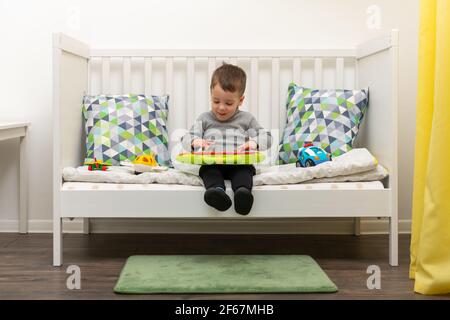 Le jeune garçon caucasien joue avec des jouets colorés Banque D'Images