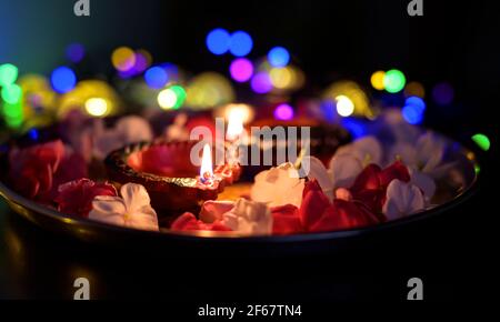 Les lampes à huile colorées de Diwali illuminent en belle formation avec des fleurs, des lumières en série dans un bokeh à l'arrière-plan pendant le festival hindou deepavali. Banque D'Images