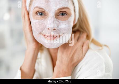Gros plan d'une femme blonde âgée avec un masque nutritionnel sur son visage, visitant des cosmetologistes dans un centre médical moderne Banque D'Images