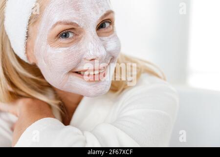 Gros plan d'une femme âgée avec un masque nutritionnel sur son visage, visitant des cosmetologistes dans un centre médical moderne Banque D'Images