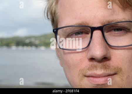 Beau jeune homme portant des lunettes souriant à la caméra Banque D'Images