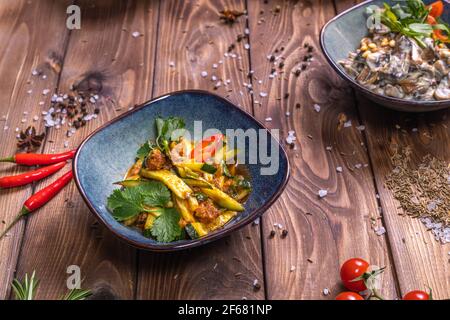 Salades de légumes dans des assiettes, tomates cerises, cannelle, romarin sur fond de bois brun. Le concept de service de restaurant. Banque D'Images