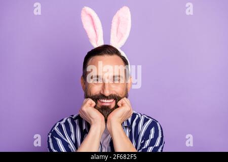 Photo d'adorable mec toothy sourire brillant poings joues porter chemise à rayures hare ears avec arrière-plan violet isolé Banque D'Images