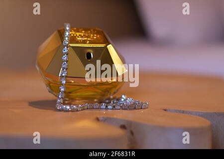 Bouteille de parfum dorée de mariée avec bracelet en losange sur table en bois. Banque D'Images