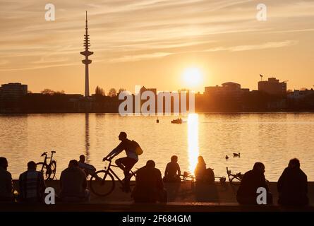 Hambourg, Allemagne. 30 mars 2021. Les gens qui profitent du soleil du soir sur les rives de l'Außenalster. La tour de télévision peut être vue en arrière-plan. Credit: Georg Wendt/dpa/Alay Live News Banque D'Images