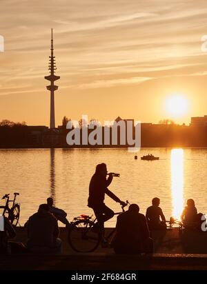 Hambourg, Allemagne. 30 mars 2021. Les gens qui profitent du soleil du soir sur les rives de l'Außenalster. La tour de télévision peut être vue en arrière-plan. Credit: Georg Wendt/dpa/Alay Live News Banque D'Images