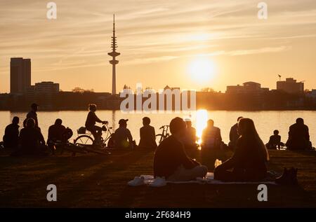 Hambourg, Allemagne. 30 mars 2021. Les gens qui profitent du soleil du soir sur les rives de l'Außenalster. La tour de télévision peut être vue en arrière-plan. Credit: Georg Wendt/dpa/Alay Live News Banque D'Images