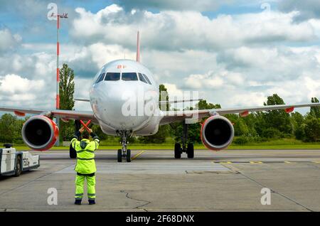 L'homme donne un panneau d'avion avec des bâtons rouges sur le tarmac Banque D'Images