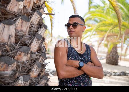 Un jeune garçon marocain pose avec des bras pliés et des lunettes de soleil en été. Banque D'Images