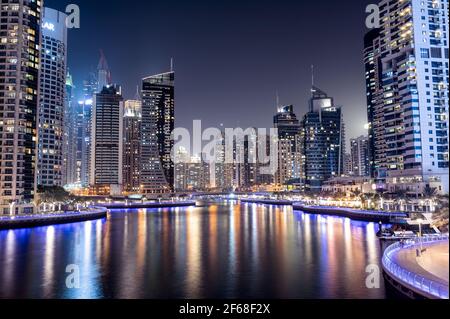 Horizon de la marina de Dubaï avec des gratte-ciel illuminés, des bâtiments et des bateaux en mouvement montrant une réflexion sur l'eau capturée à Marina Mall, Dubaï, Émirats Arabes Unis. Banque D'Images