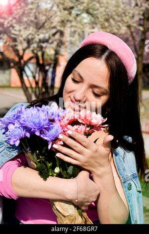 Belle femme tenant des fleurs roses et pourpres à l'extérieur Banque D'Images