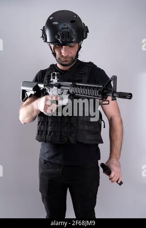 Un seul militaire qui recharge son arme tout en portant un équipement de protection. Studio tourné isolé Banque D'Images