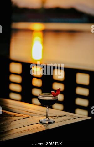 cocktail sombre garni d'une touche orange sur un bar sombre. Banque D'Images