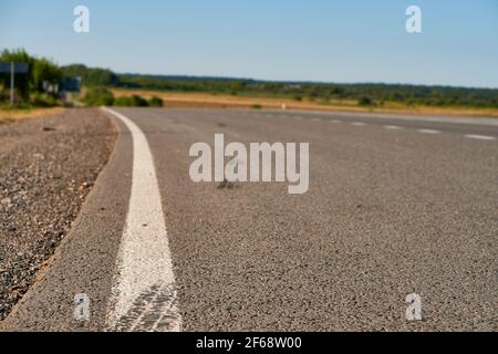 surface asphaltée à mise au point douce avec marquages blancs à proximité de la surface basse. route de campagne et champ avec forêt en été. Haute qualité Banque D'Images