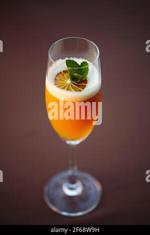 Verre de cocktail d'orange décoré avec une garniture orange au bar arrière-plan du compteur Banque D'Images