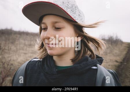 Gros plan d'un garçon aux cheveux longs lors d'une promenade avec un sourire malicieux. Banque D'Images