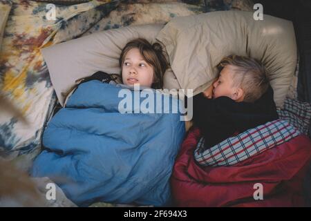 Deux amis côte à côte dans des sacs de couchage. On a l'air peur. Banque D'Images