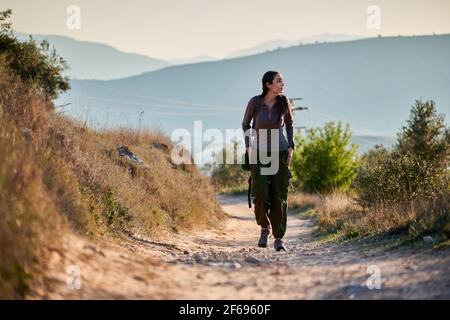 Une femme explorer marche le long d'une route de terre observant la nature Banque D'Images