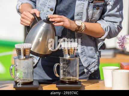 Préparation goutte à goutte, le barista prépare du café filtre frais au café extérieur. Premier jour de printemps avec un soleil chaud et lumineux après un long hiver. Banque D'Images