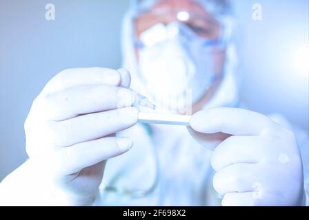 Un médecin portant un masque chirurgical et des gants chirurgicaux tenant un Covid-19 (virus corona) à l'aide d'un test rapide , sur fond blanc. Banque D'Images