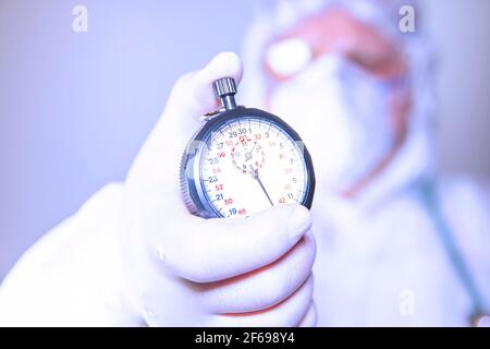Un médecin portant un masque chirurgical et des gants chirurgicaux tenant un chronomètre pour une action rapide afin de résister à la propagation du covid 19 et à la vaccination. Sur fond blanc Banque D'Images