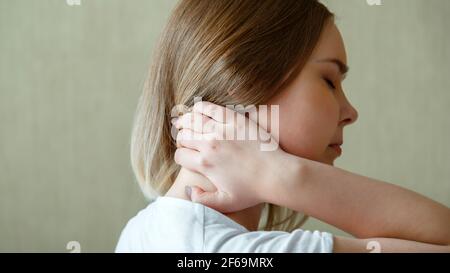 La femme tient le cou avec douleur spasme du muscle cervical à la main. Douleurs au cou, vertèbres cervicales, maladie du système musculo-squelettique chez la jeune femme. Bande longue Banque D'Images