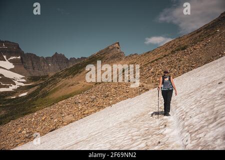 Une femme traverse un champ de neige qui couvre la piste jusqu'au col de Piegan Parc national des Glaciers Banque D'Images