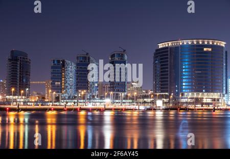 Vue sur les bâtiments admirablement illuminés Jewel of the creek avec le pont flottant, capturé du parc de la crique, Dubaï, Émirats arabes Unis. Loisirs et voyages Banque D'Images