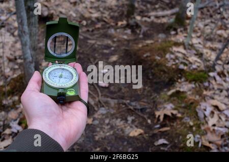 Une image point de vue montrant une main tendue qui pose une boussole prismatique à plat sur elle pour naviguer dans les bois. Banque D'Images