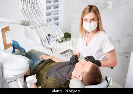 Jeune homme recevant un traitement orthodontique dans le cabinet dentaire. Banque D'Images