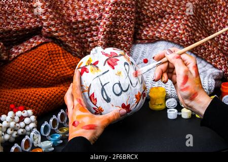 BRICOLAGE. Faites-le vous-même. Une femme peint des décorations d'action de grâce sur la citrouille d'orange pour Halloween. Récolte d'automne. Banque D'Images