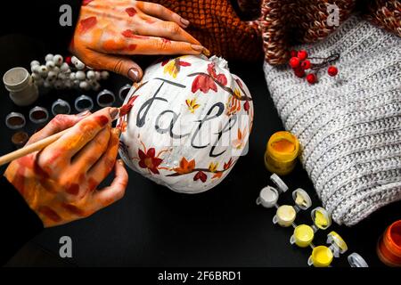 BRICOLAGE. Faites-le vous-même. Une femme peint des décorations d'action de grâce sur la citrouille d'orange pour Halloween. Récolte d'automne. Banque D'Images