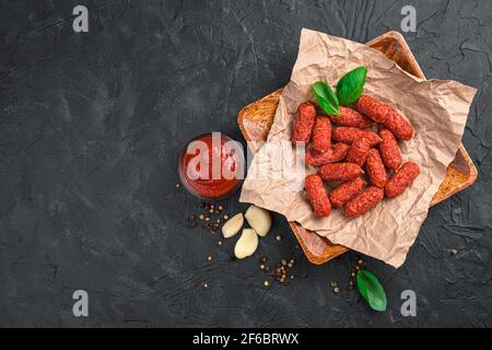 Saucisses Mani à l'ail avec sauce dans une assiette en bois sur fond noir. Banque D'Images