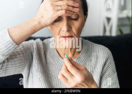 Mère âgée d'âge moyen, grande-mère souffrant de maux de tête ou de migraine chroniques importants, de stress et de vertiges, de fatigue physique et mentale, de prise de pilules et de prise de médicaments Banque D'Images