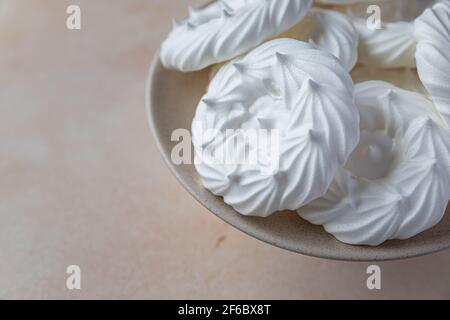 Assiette avec nids de meringue vides, fond de pierre clair. Concept pour un délicieux dessert sucré. Mise au point sélective. Banque D'Images