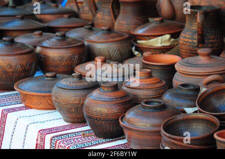 Cruches traditionnelles en céramique sur la serviette décorative. Vitrine de la poterie de céramique d'Ukraine faite à la main dans un marché de l'assistance routière avec des pots en céramique et des plaques d'argile. Banque D'Images