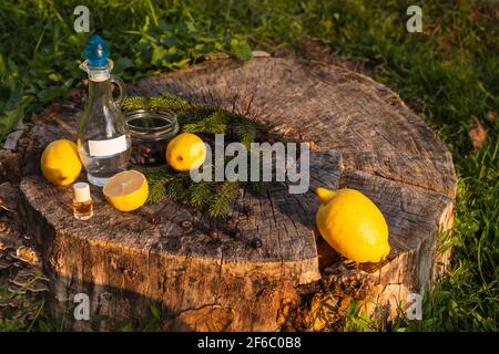 Huile essentielle de citron en bouteille, vinaigre en verre, tranches de fruits frais sur fond de bois.Parfums naturels Banque D'Images