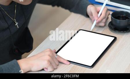 Photo rognée d'un homme tenant un stylet pointant sur l'écran d'une tablette numérique. Banque D'Images