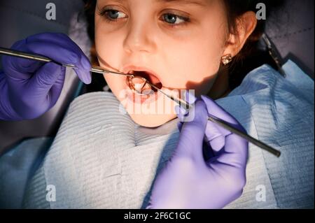 Dentiste féminin examinant les dents de petite fille dans le cabinet dentaire. Banque D'Images