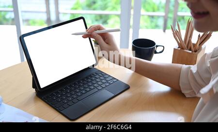 Photo rognée d'une femme comptable travaillant avec une tablette d'ordinateur et tenant un stylet pointant sur l'écran. Banque D'Images