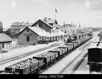 Eskilstuna Maison centrale de la vieille gare, vue depuis le chemin de fer. La gare a été construite par Oxelösund - Flen - Västmanland Railway, OFWJ, 1876. Le nom Eskilstuna Central a été ajouté 1895 lorsque le chemin de fer de Norra Södermanland a ouvert Eskilstuna au nord et la gare Esilstuna Södra. La gare en face de la gare est l'une des sept locomotives que l'OFWJ a acquises de Stewart Manchester Angleterre 1874-1875. Où la rainure au centre de l'image, un certain nombre de wagons de minerai à trois axes de l'OFWJ et du rail frövi-Ludvika, suivent. Y compris OFWJ 682.I l'arrière-plan a vu l'église Fors. Banque D'Images